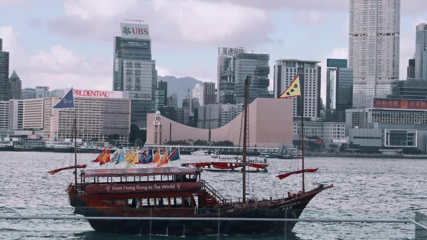 Traditional boat sailing in hong kong harbor with skyscrapers in the background