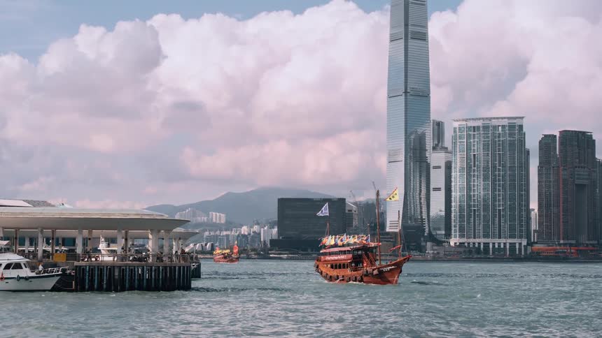 The orange boat moves past the buildings