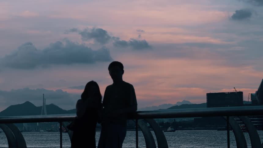 People watching the sunset by the sea with pink hues in the sky