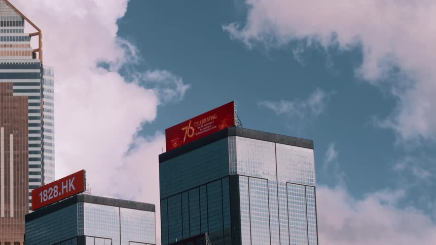 The tops of some modern skyscrapers against a cloudy blue sky