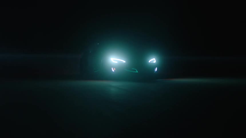 A car drives at night with its headlights on