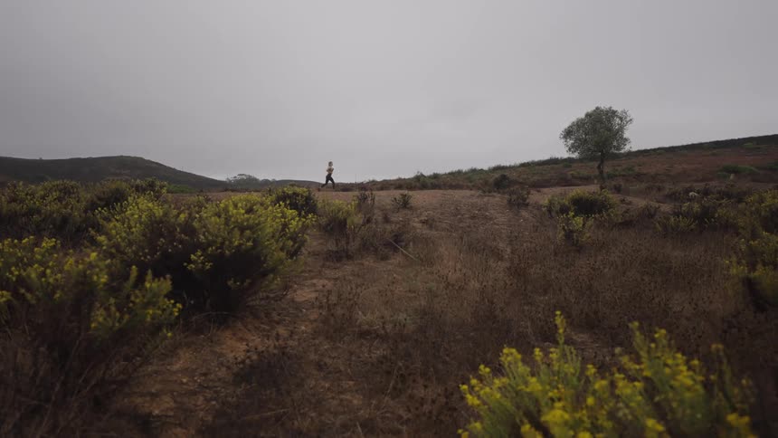 A young woman running outdoors on a road in a grassland area during daytime