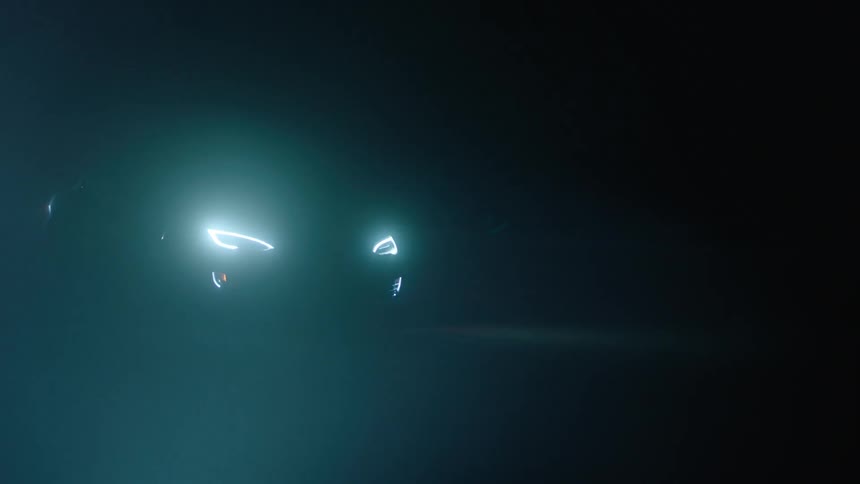 A car drives at night with its headlights on