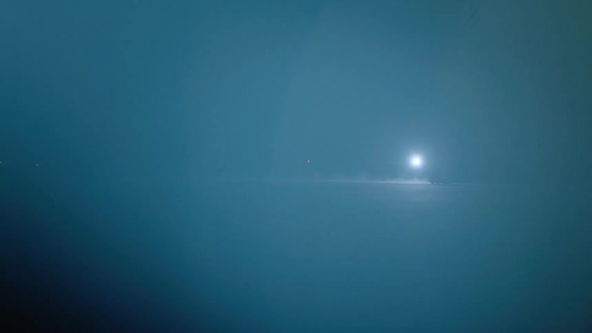 A truck drives by a bright light at night