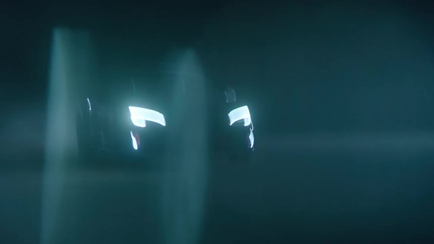 A car drives through an empty parking lot at night