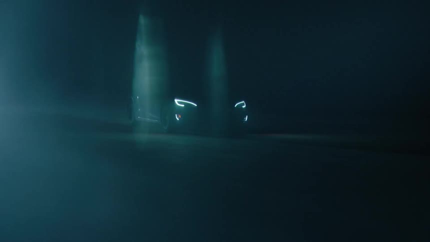 A car drives at night with its headlights on