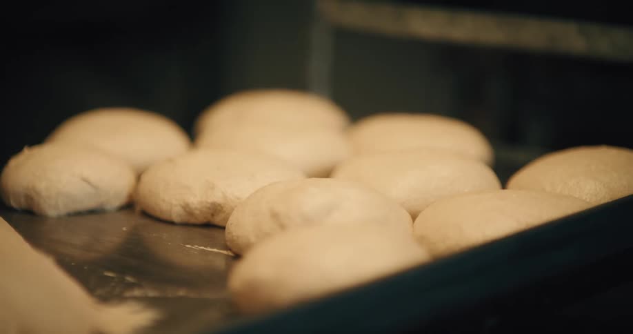 Close up shot of several balls of unbaked dough on a metal tray ready to go into an oven