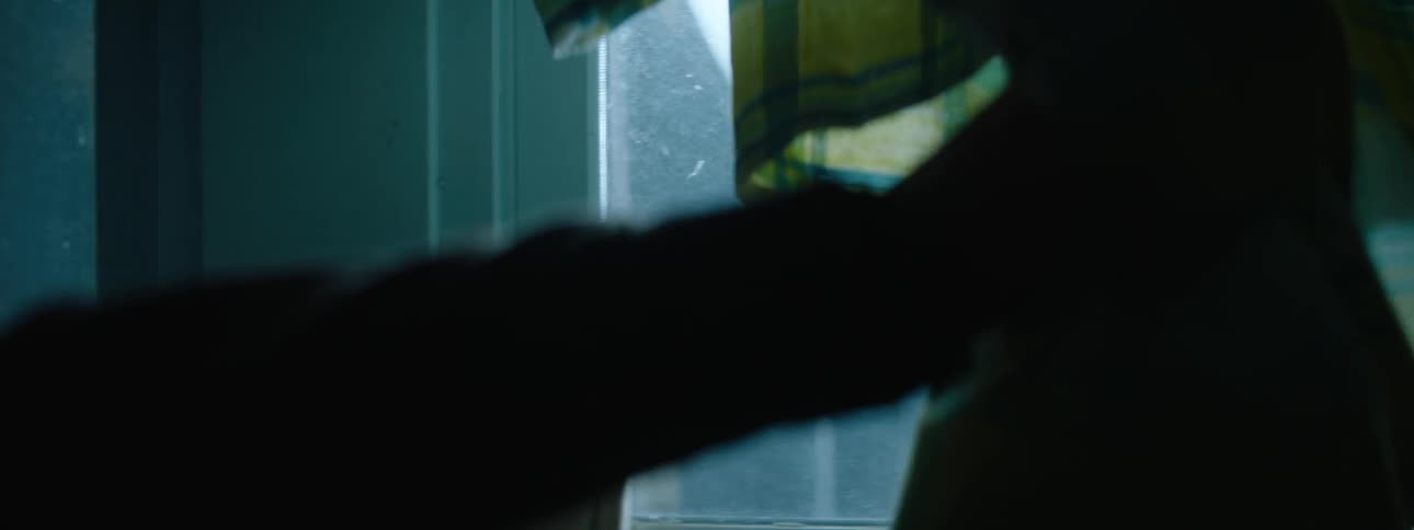 A person pulls the curtain back to look out the window
