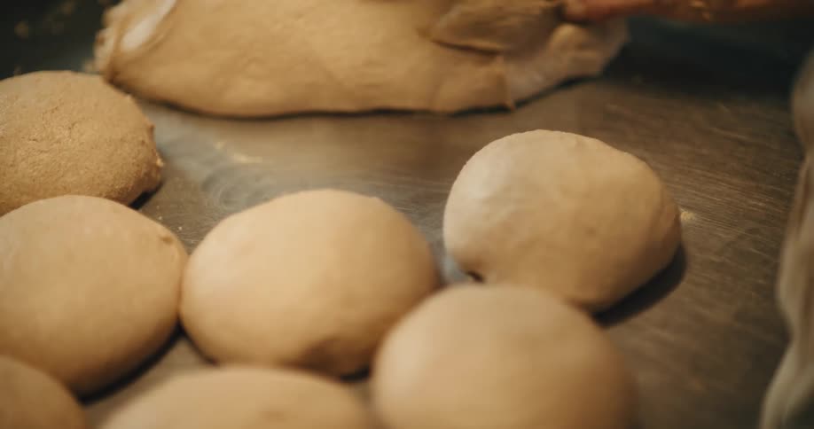 Hands shaping portions of dough on a floured countertop