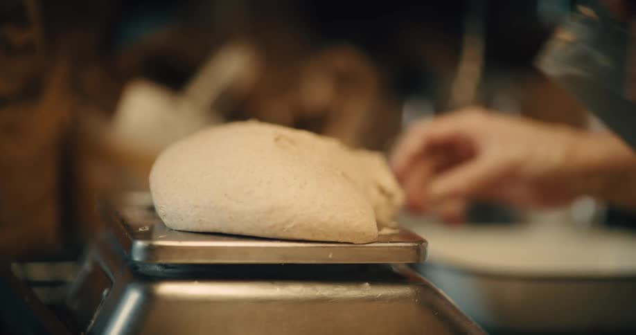 Dough is placed on metal kitchen scales