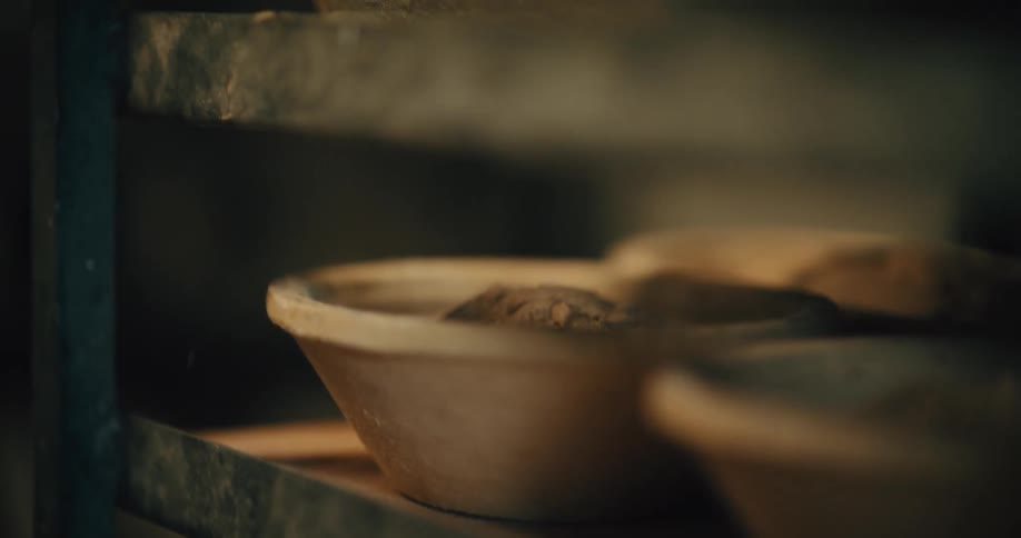 Hand placing a bowl of dough on a bakery shelf
