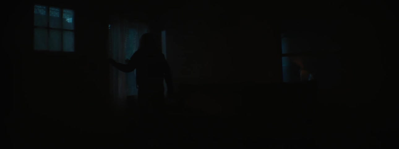 A woman gets off the couch and looks out the window