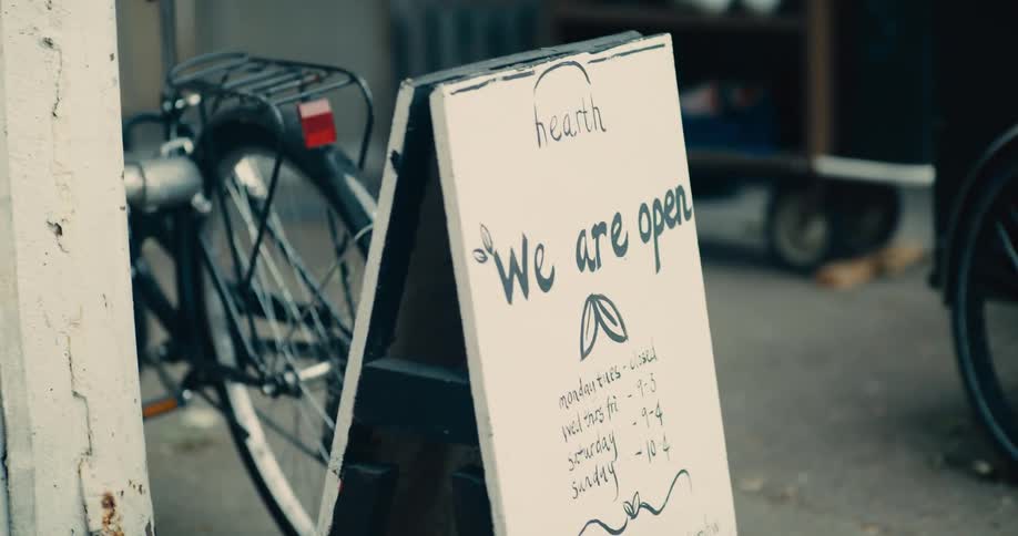 A sign is on the sidewalk outside of the store