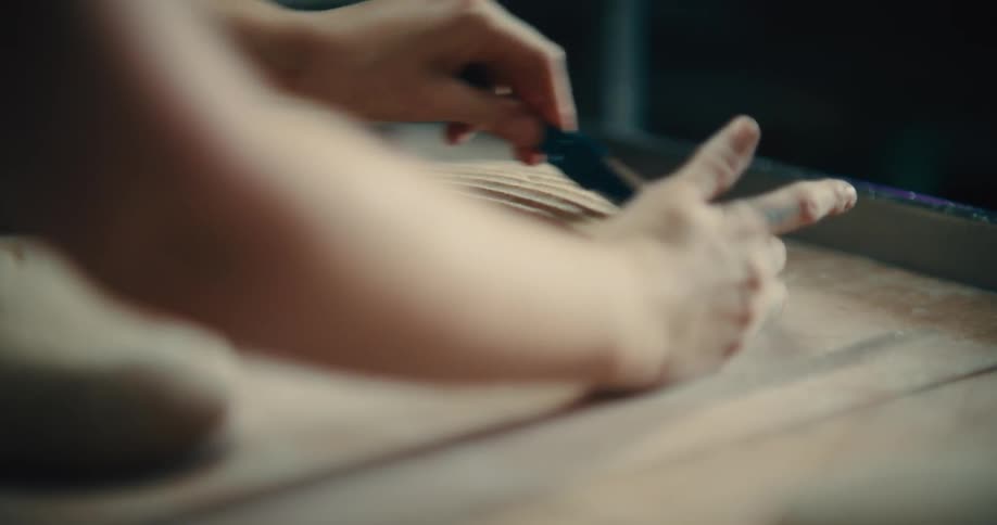 A baker makes several quick parallel cuts across the surface of dough