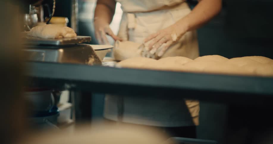 Male baker working on bread dough at a professional kitchen indoors