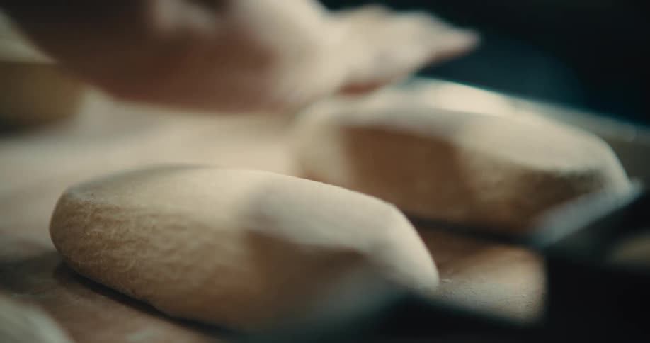 Bread dough being handshaped on a floured counter