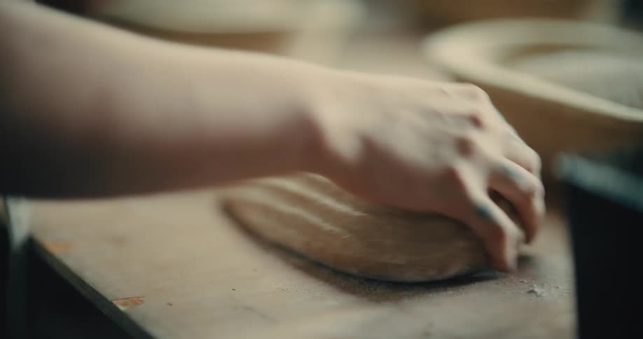 Close up of a woman turning bread dough from their containers to a table top