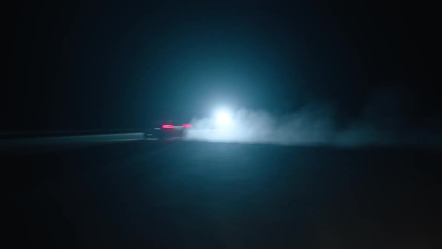 A car is racing down the road at night