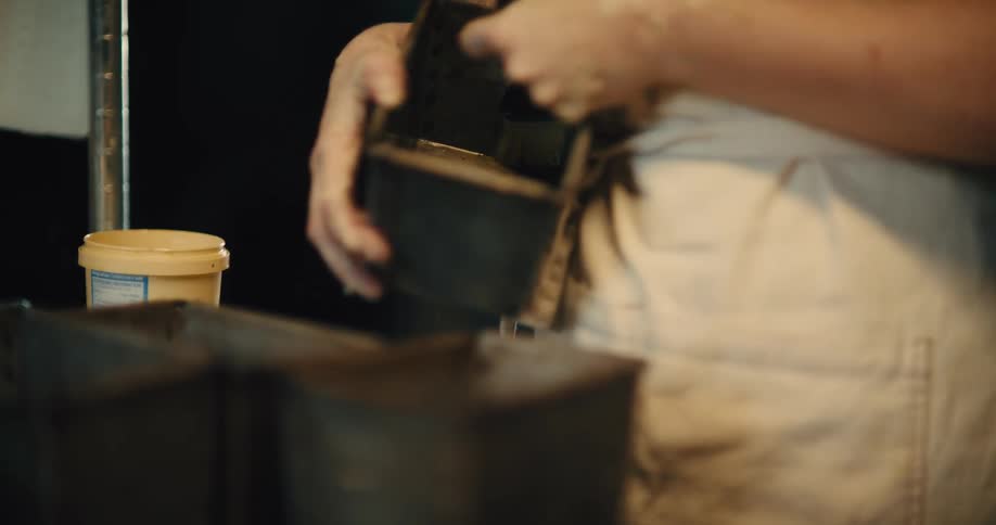 Person greasing a metal pan before placing the bread dough