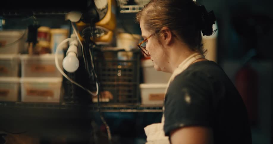 Person working in a bakery with a shelf full of utensils and ingredients