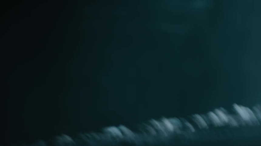 A car drives with its headlights on at night