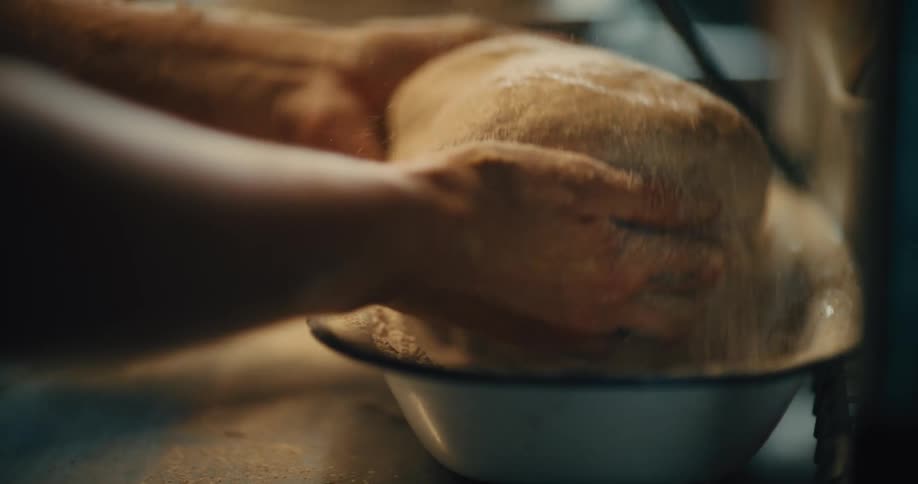 Close up of a woman dipping baking dough into a bowl containing flour powder