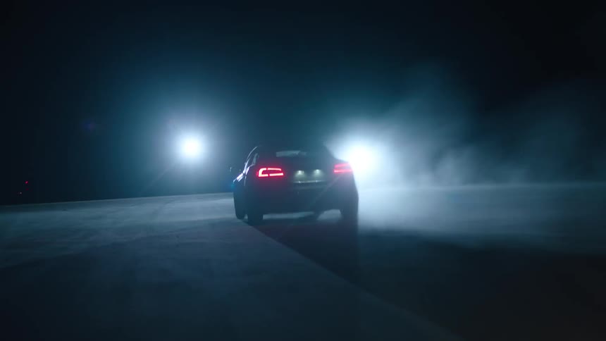 Car driving on pavement at night towards two bright lights