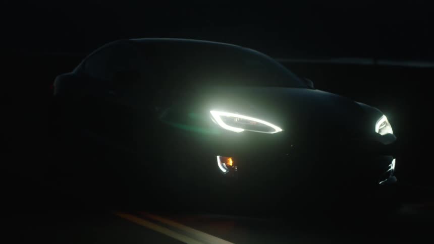 A car drives at night with its headlights on