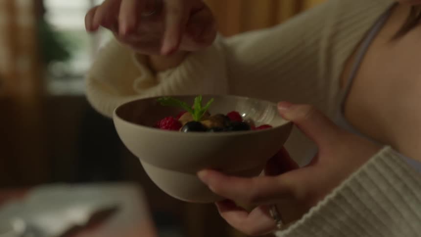 A woman places fruit in a bowl