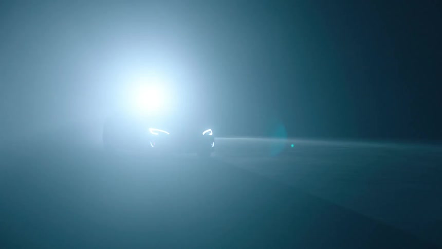A car with bright lights is going down the road at night