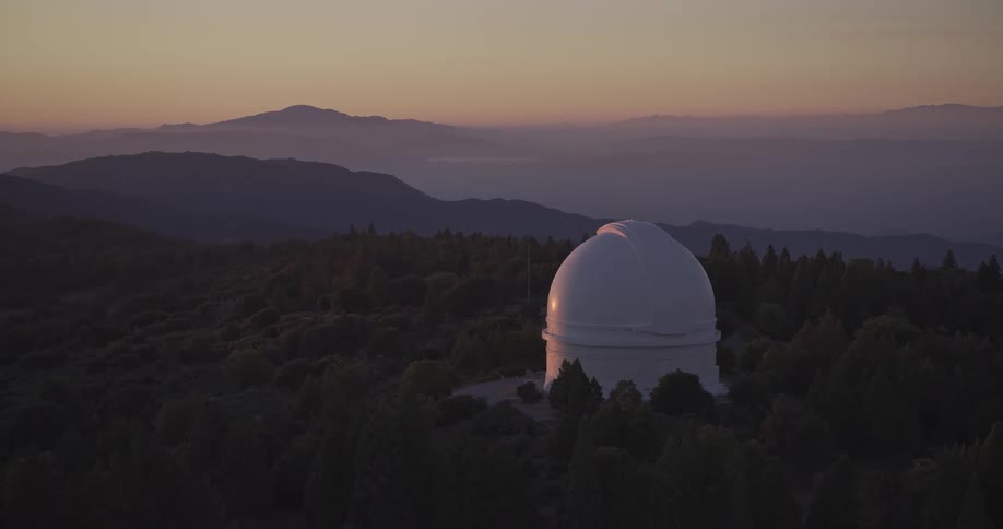 White observatory surrounded by trees during sunset in the mountains