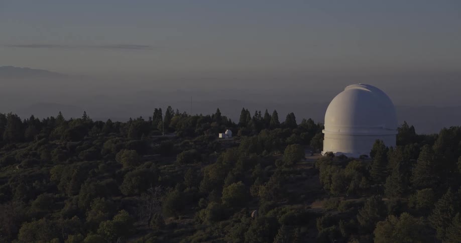 Aerial of an observatory outdoors in a forest area at sunset