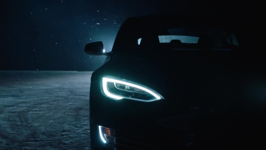A car sits in a snowy parking lot at night