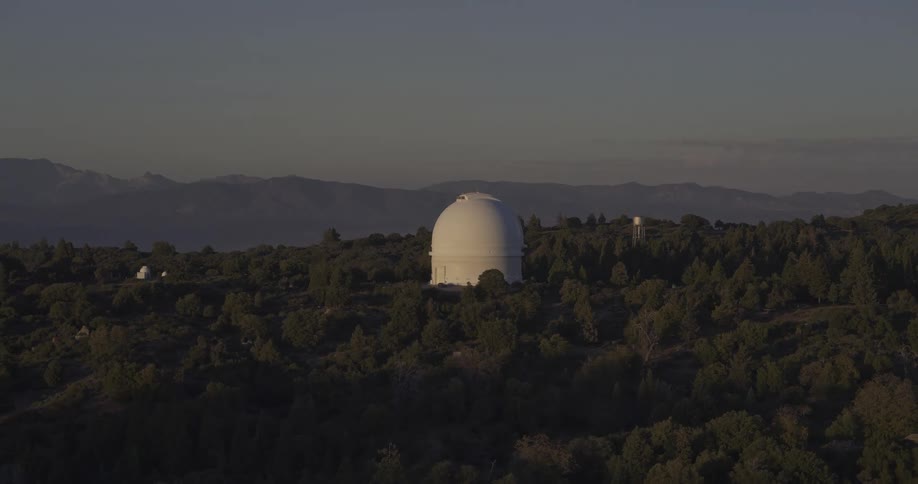 White observatory amid treecovered hills under the soft light of evening