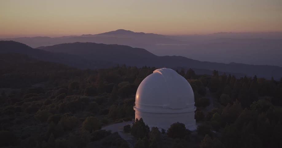 Observatory dome reflecting the sunset light among mountains