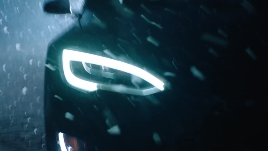 Falling snow shines in a car's headlights