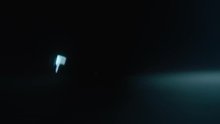 A car speeds through a dark parking lot