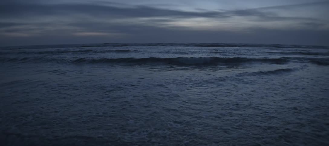 Sea waves flowing towards the shore outdoors at dusk