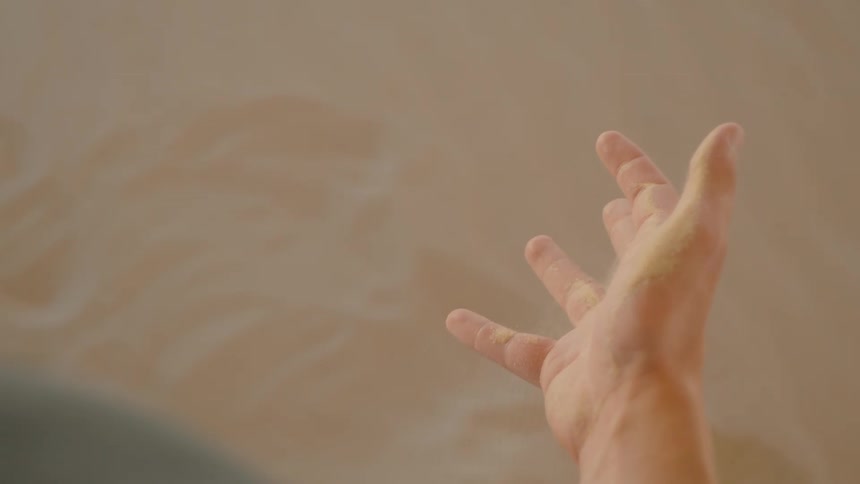 Male human hand dropping sand from its palm outdoors during day time