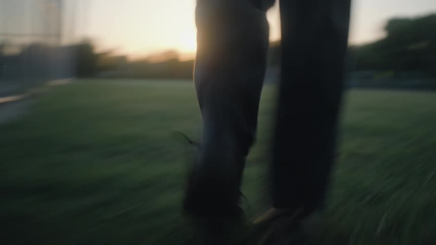 The video is an extreme closeup shot of a small bright sun flare filtering through what appears to be a chainlink fence the sun is low in the sky creating a golden hazy glow around the dark vertical fence posts in the foreground