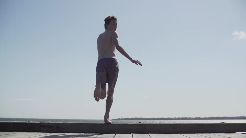 Man running down a boardwalk then jumping into the water