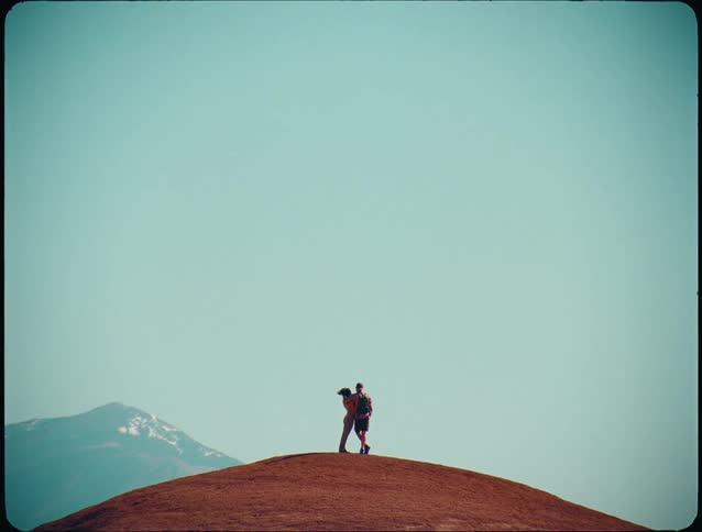 The man and woman stand on the windy hill