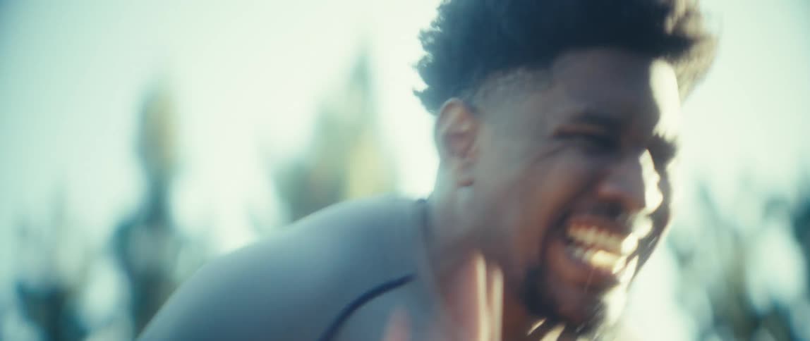 Young black man panting and looking exhausted then doing a round of running in place on a field outdoors during day time
