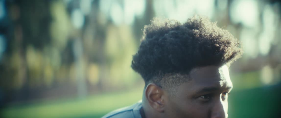 The video begins with an overexposed bright shot of a man hunched over transitioning to a closeup of his facehe is smiling and then immediately shifts to a look of intense focus as he starts to sprint forward indicating a moment of comp