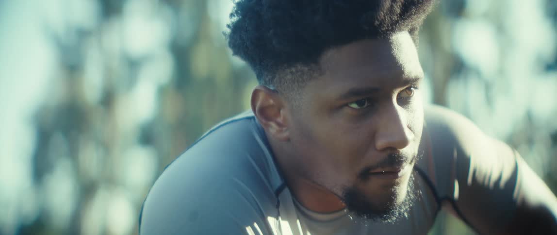 A focused athlete catches his breath in the hazy bright sunlight during a break from his workout