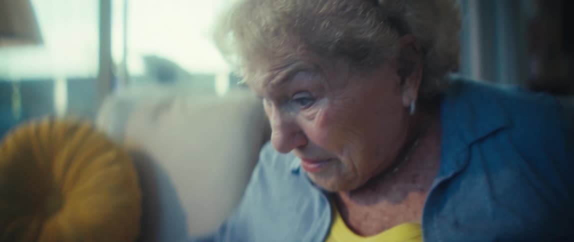 Elderly lady sitting and petting a dog lying next to her
