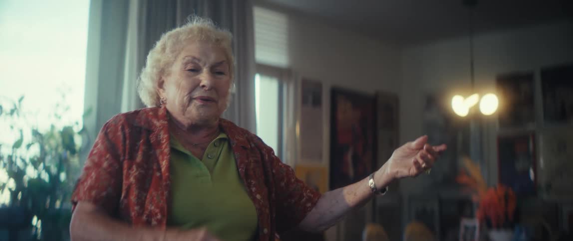 Elderly woman plays air guitar while in her living room alone during the daytime