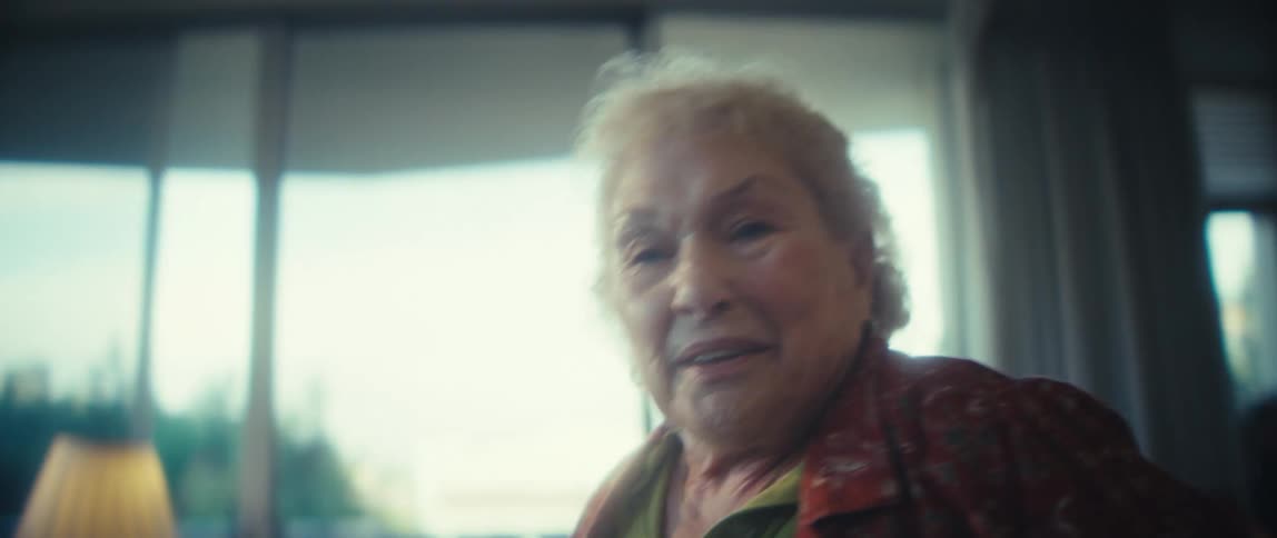 An elderly woman in her home dances turning with a warm smile