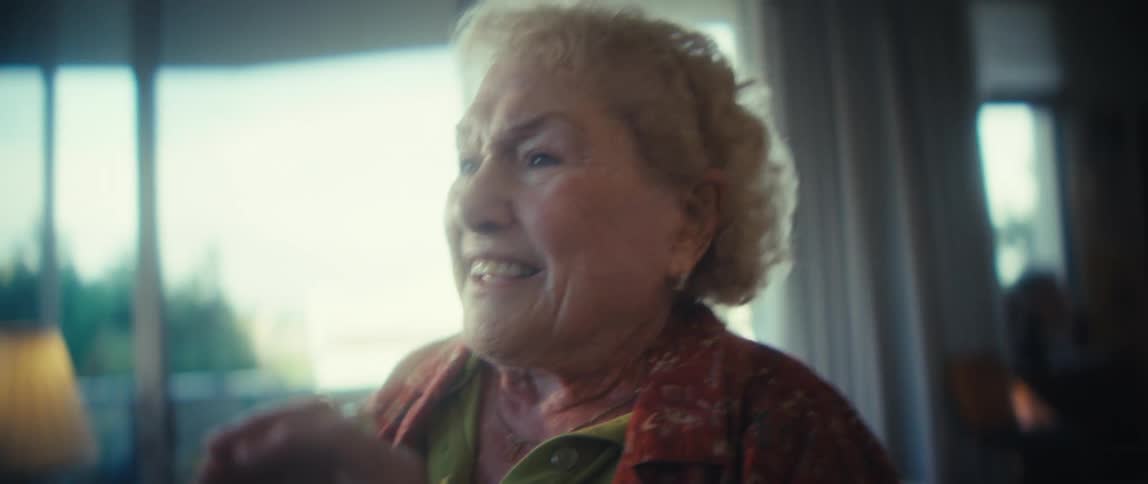 Smiling elderly woman in an indoor setting lit by natural window light
