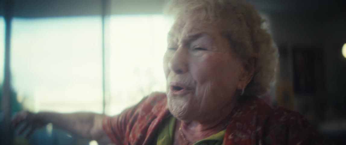 Elderly woman smiles while dancing alone at home during the daytime
